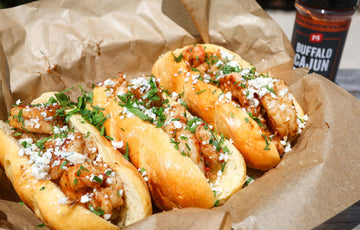 3 Brown Butter Shrimp Rolls topped with bleu cheese crumbles and parsley in a food basket with brown paper. Buffalo Cajun Wing Rub in the background. 