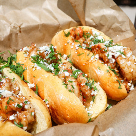 3 Brown Butter Shrimp Rolls topped with bleu cheese crumbles and parsley in a food basket with brown paper. Buffalo Cajun Wing Rub in the background. 